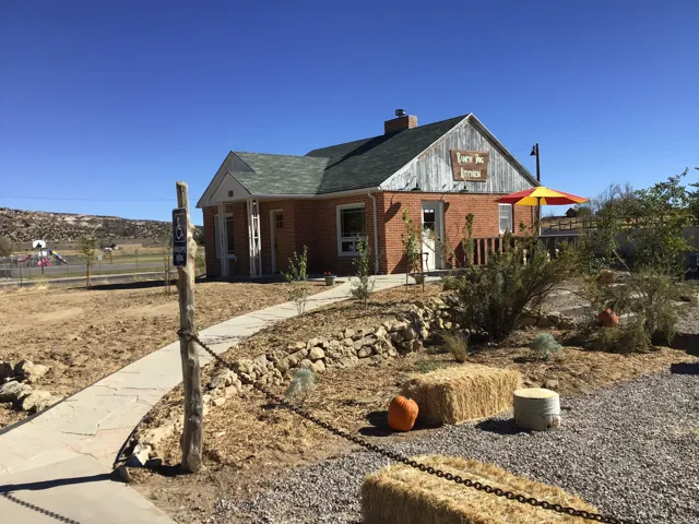 View of front of home featuring a porch, a chimney, brick siding, and a shingled roof