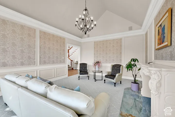 Living room featuring a decorative wall, wainscoting, wallpapered walls, lofted ceiling, and ornamental molding