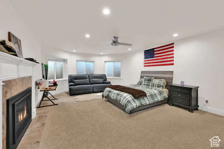 Bedroom featuring a tile fireplace, recessed lighting, light colored carpet, and ceiling fan