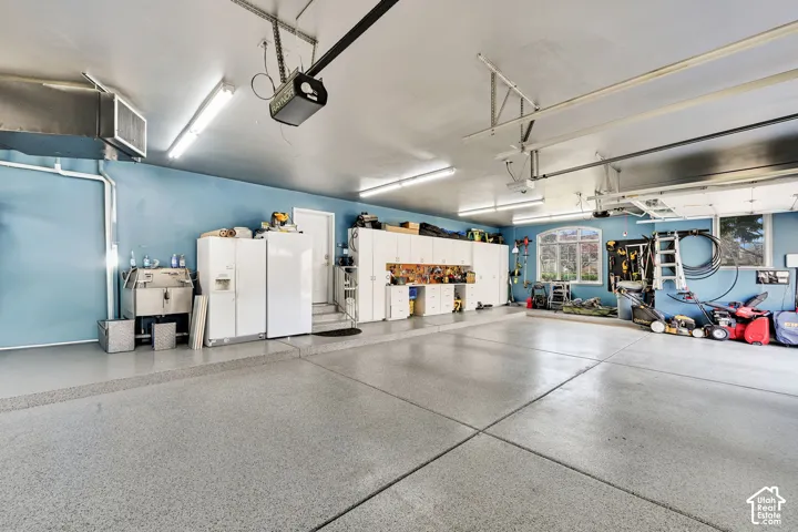 Garage with white fridge with ice dispenser, freestanding refrigerator, and a garage door opener