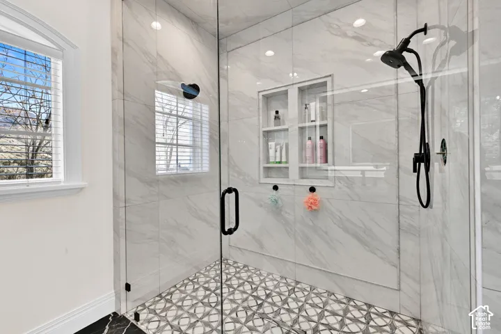 Full bath featuring a marble finish shower and healthy amount of natural light