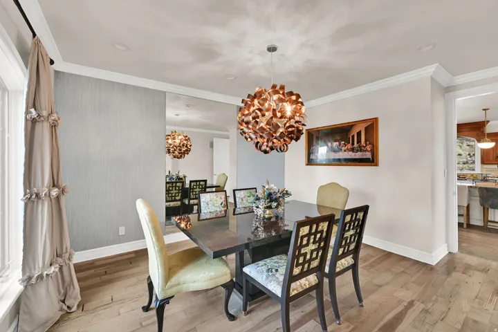 Dining space with crown molding, light wood-type flooring, and suspended lighting