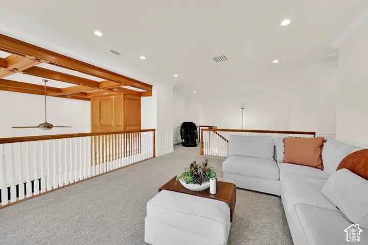 Carpeted living room with crown molding, a ceiling fan, recessed lighting, and a wainscoted wall