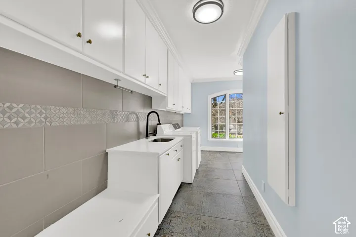 Laundry area with ornamental molding, stone tile flooring, cabinet space, and independent washer and dryer