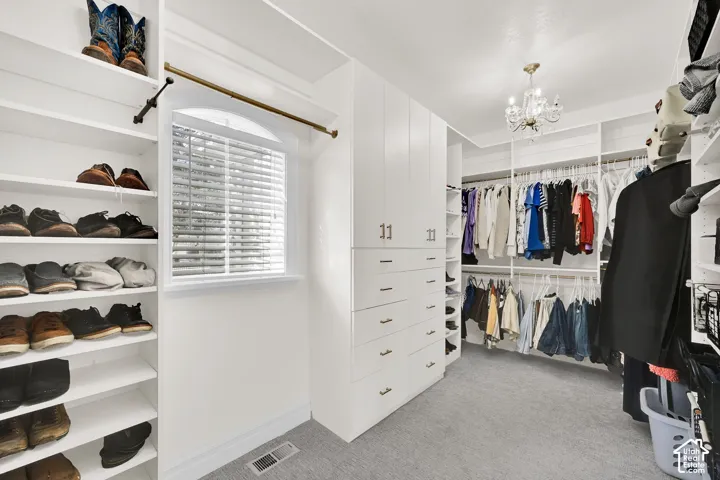 Walk in closet featuring light colored carpet and hanging lights