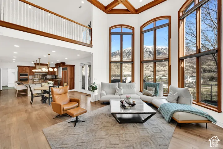 Living area with recessed lighting, a mountain view, coffered ceiling, light wood-style flooring, and crown molding