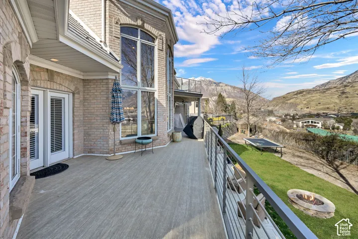 Wooden deck featuring a fire pit, a mountain view, and a yard