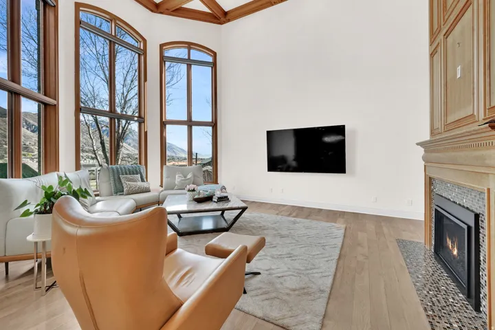 Living room with a tiled fireplace, light wood-style flooring, and coffered ceiling