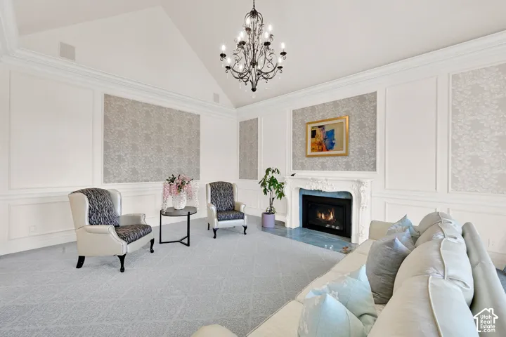 Carpeted living area featuring a decorative wall, a premium fireplace, a chandelier, and vaulted ceiling