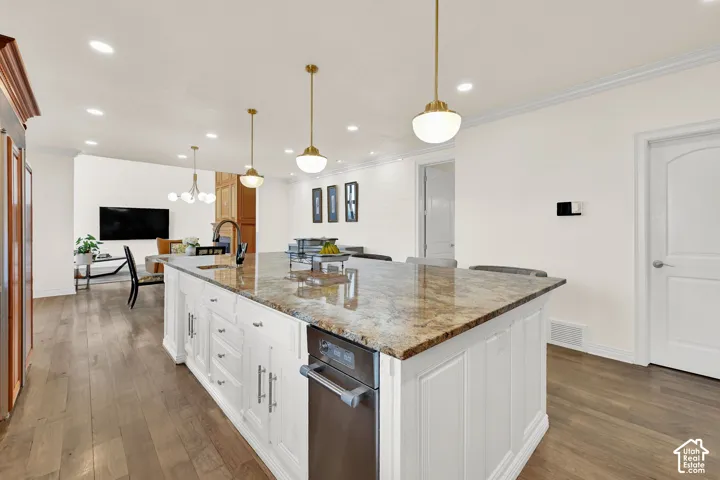 Kitchen featuring dark stone counters, dark wood-style floors, a large island, white cabinetry, and ornamental molding