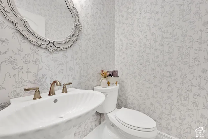 Half bath with wallpapered walls and a sink