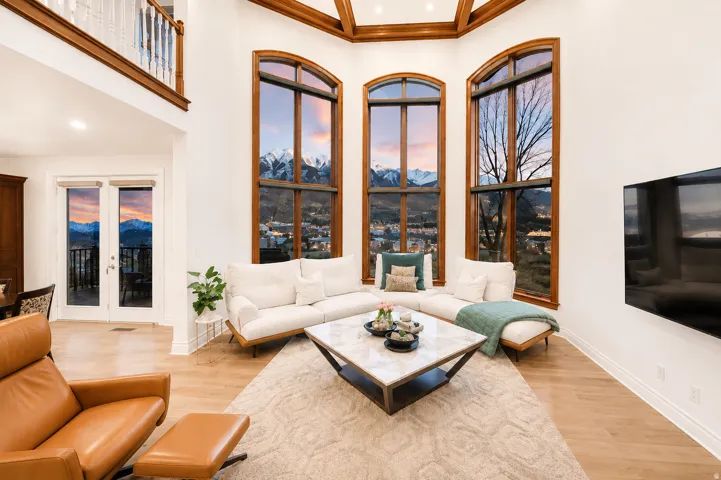 Living area featuring a high ceiling, wood-finish flooring, and a second-story interior balcony with white balusters