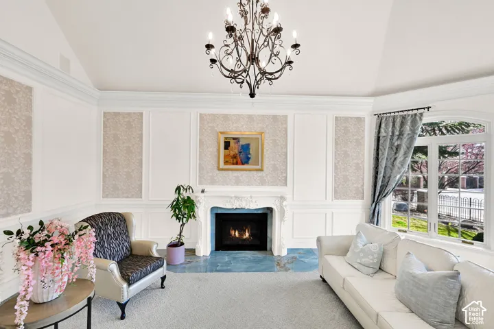 Living area featuring a decorative wall, a premium fireplace, vaulted ceiling, and a chandelier