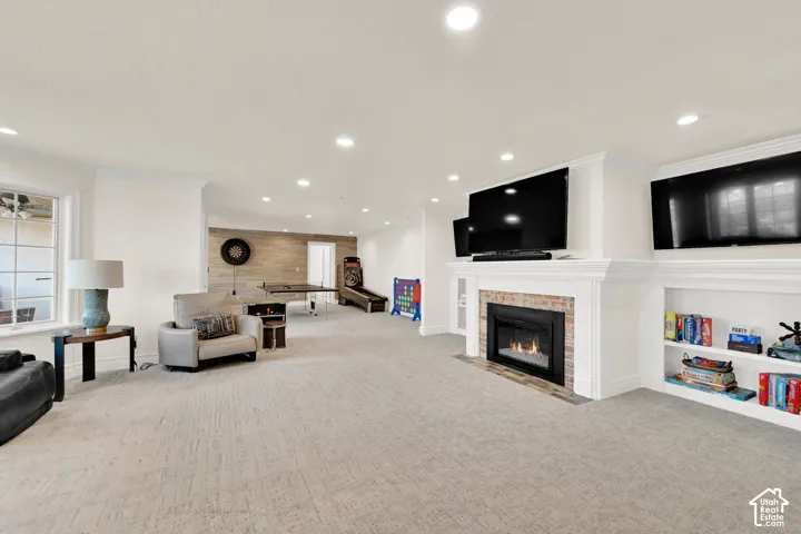 Living room featuring light carpet, ornamental molding, recessed lighting, and a fireplace with flush hearth