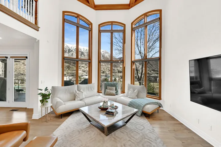 Living room featuring a high ceiling, light wood finished floors, and crown molding