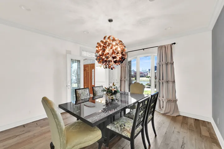 Dining room with crown molding, light wood finished floors, and a chandelier