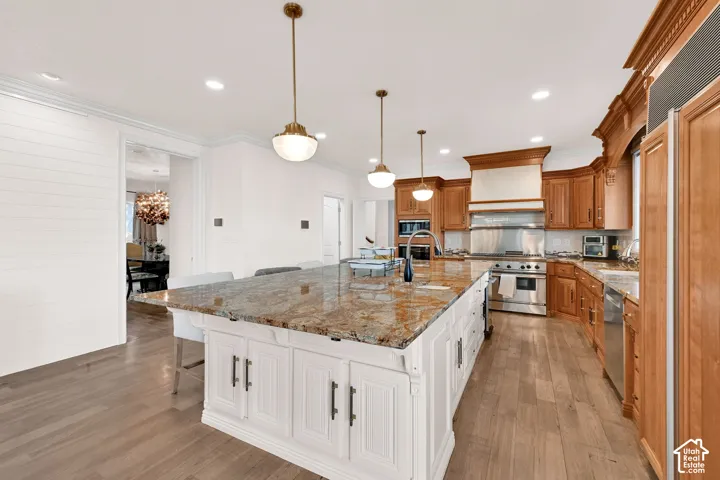 Dual tone kitchen featuring dual tone cabinetry, a breakfast bar area, light stone countertops, a large island, and pendant lighting