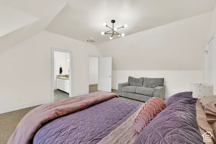 Bedroom with lofted ceiling, carpet, connected bathroom, and hanging lights