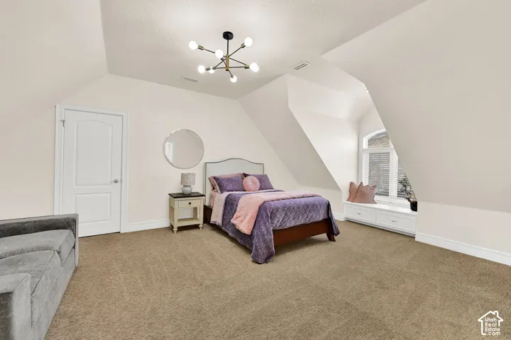 Bedroom with light colored carpet and hanging lights