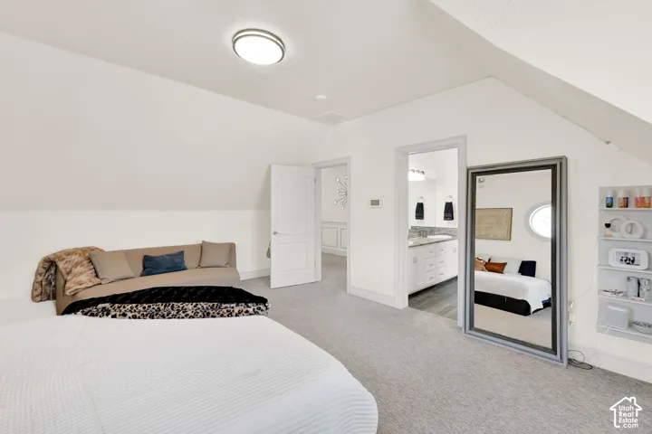 Bedroom featuring light carpet and ensuite bathroom