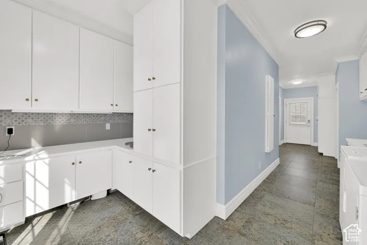 Laundry area featuring ornamental molding and stone tile floors
