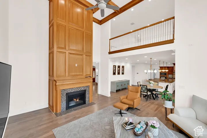 Living room featuring light wood finished floors, a tile fireplace, a high ceiling, a ceiling fan, and recessed lighting