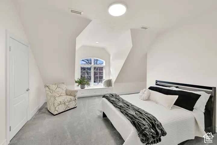 Carpeted bedroom featuring lofted ceiling and baseboards