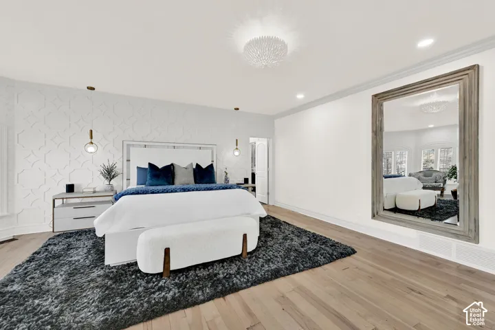 Bedroom featuring light wood-style floors, an accent wall, recessed lighting, wallpapered walls, and crown molding