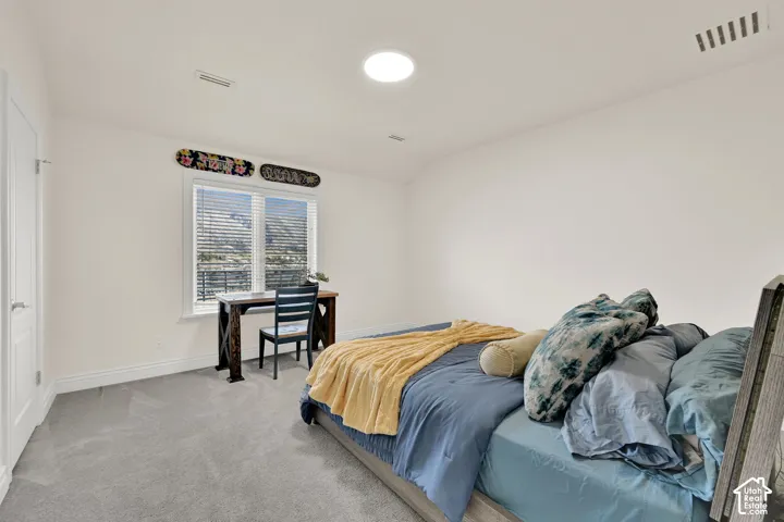 Bedroom featuring light colored carpet and vaulted ceiling
