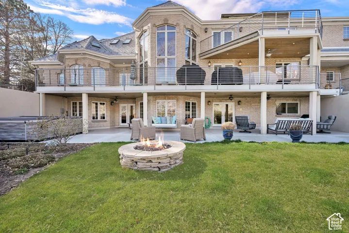 Back of house featuring an outdoor living space with a fire pit, a patio, french doors, a balcony, and ceiling fan
