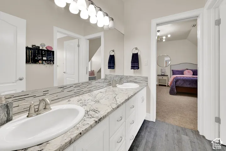 Ensuite bathroom with double vanity and dark wood finished floors