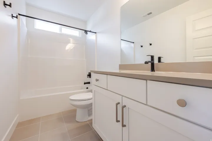 Bathroom featuring a white vanity with a light-colored countertop, matte black faucet, and a large wall-mounted mirror