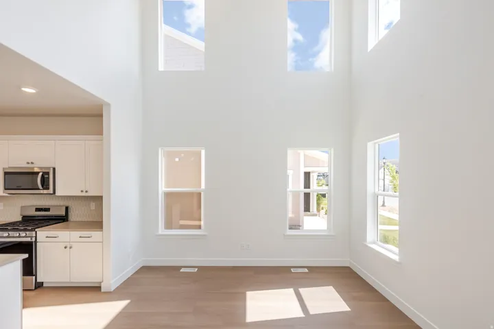 Two-story ceiling with multiple windows and wood-finish flooring