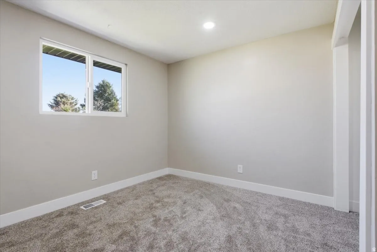 Empty room featuring light carpet and baseboards