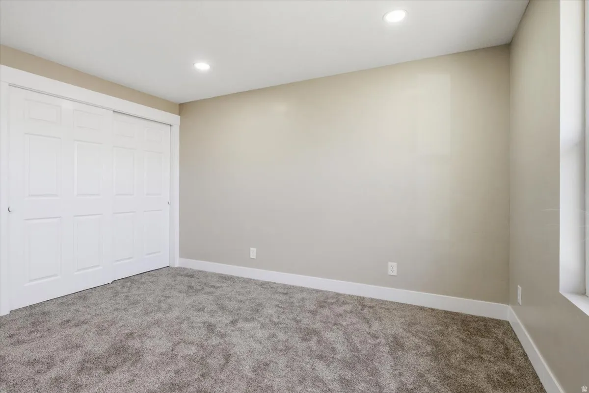 Unfurnished bedroom with carpet flooring, a closet, and recessed lighting