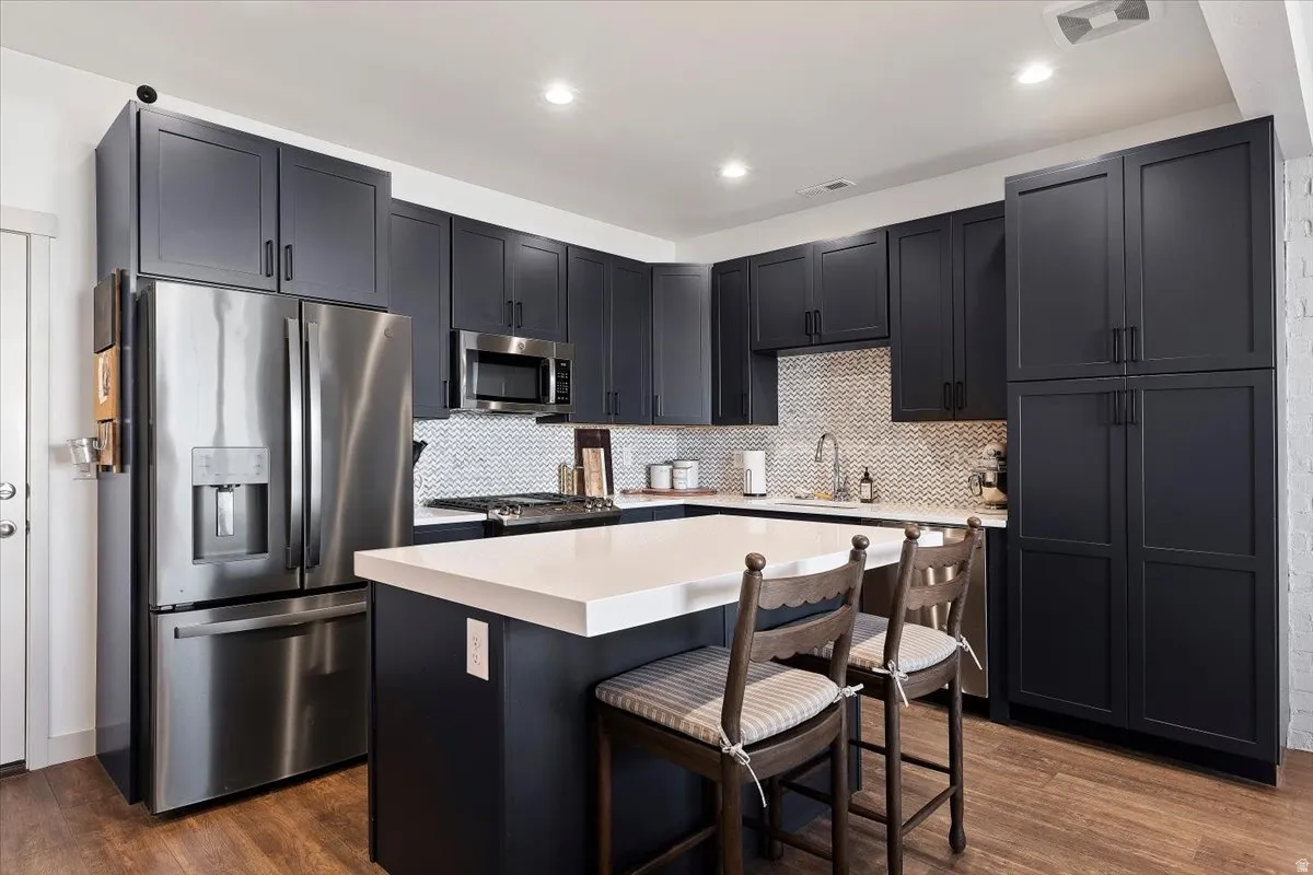 Kitchen featuring stainless steel appliances, a center island, a breakfast bar area, dark cabinetry, and recessed lighting