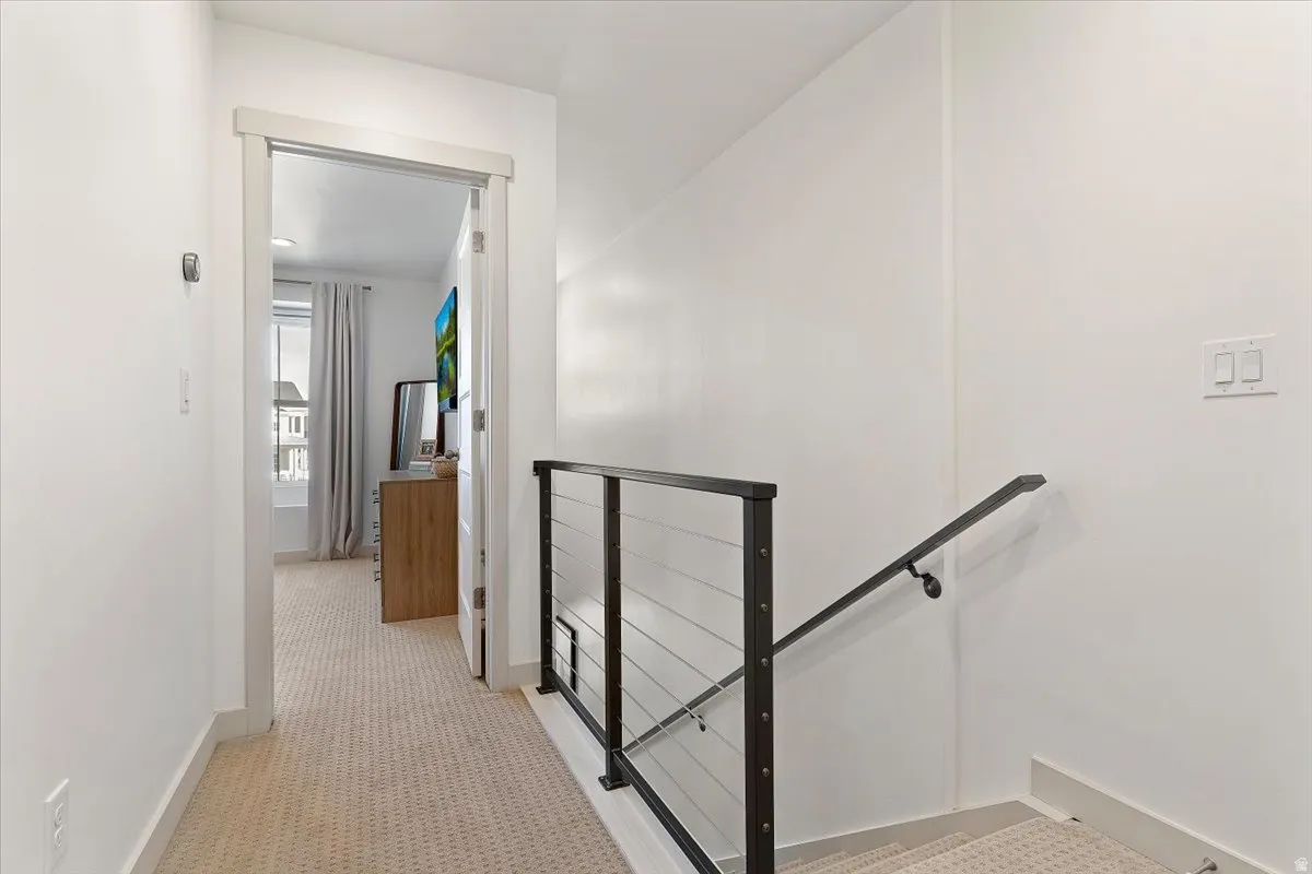 Hallway with an upstairs landing and light colored carpet