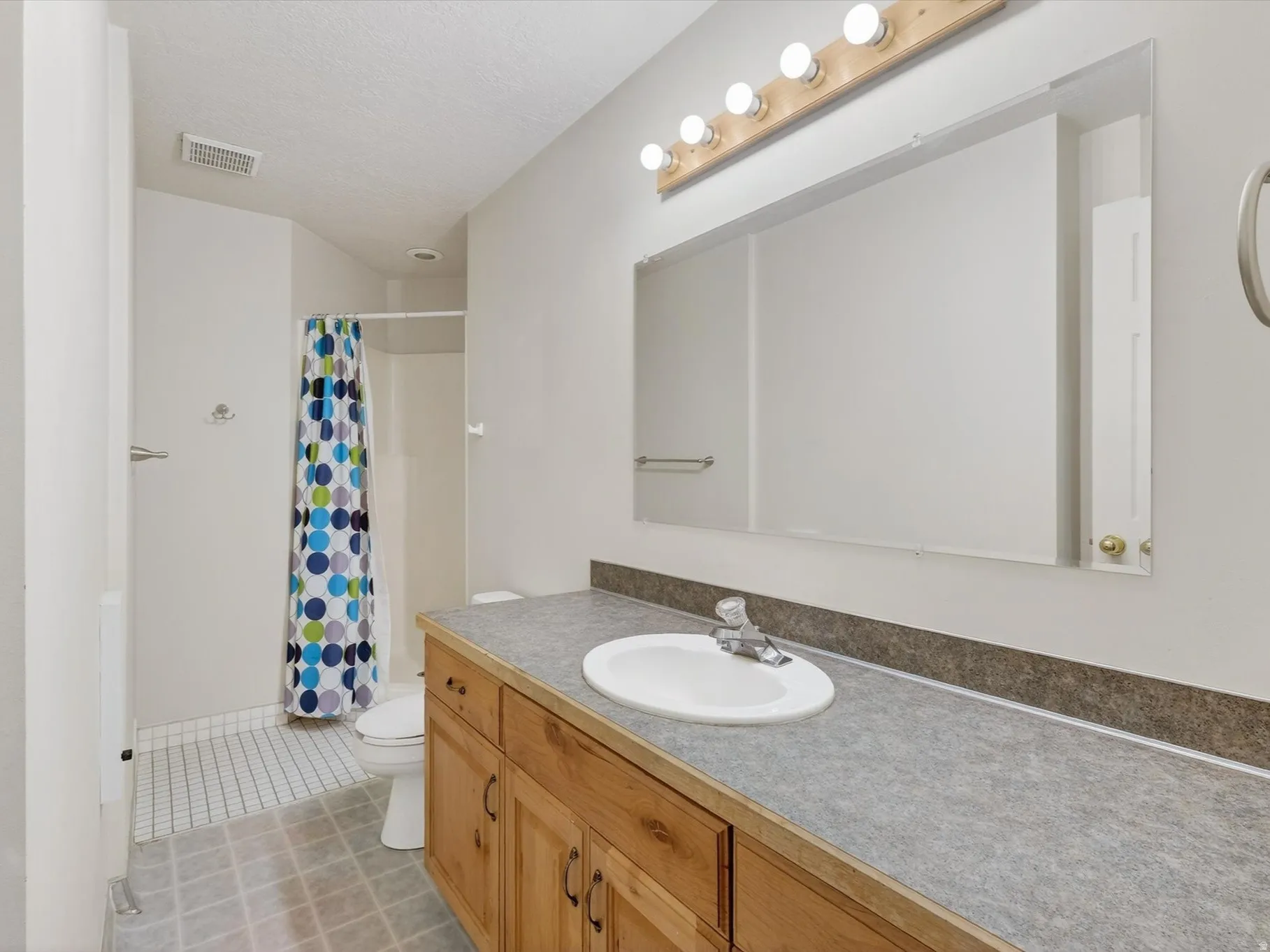 Bathroom featuring vanity, a shower with shower curtain, and light tile patterned floors