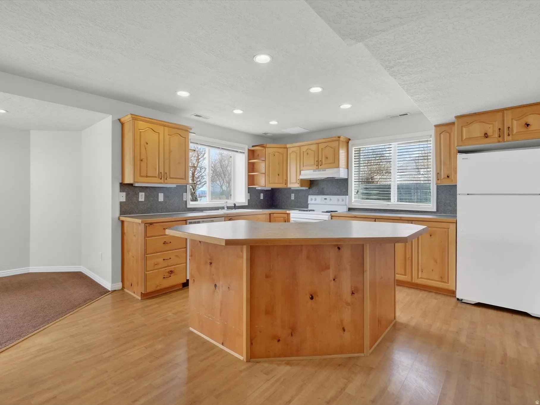 Kitchen featuring white appliances, a kitchen island, decorative backsplash, healthy amount of natural light, and recessed lighting