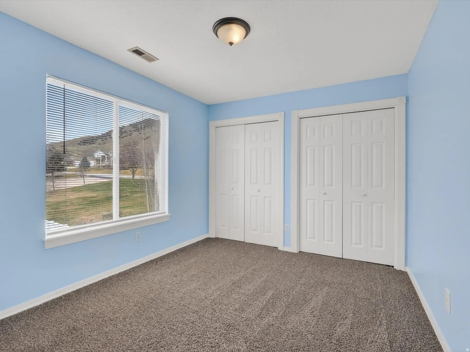 Unfurnished bedroom featuring two closets and dark carpet