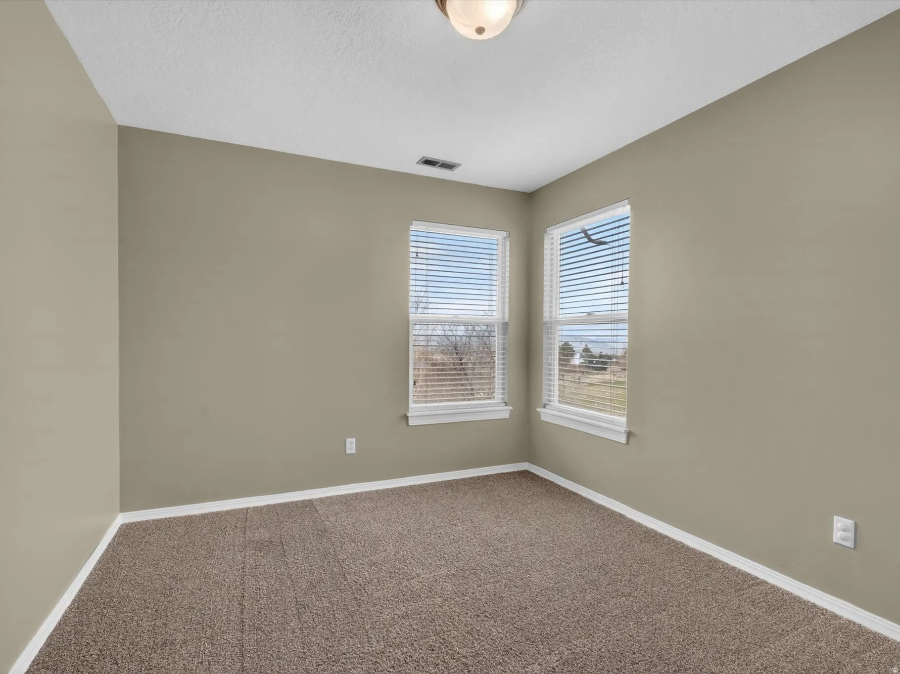 Carpeted spare room with baseboards and a textured ceiling