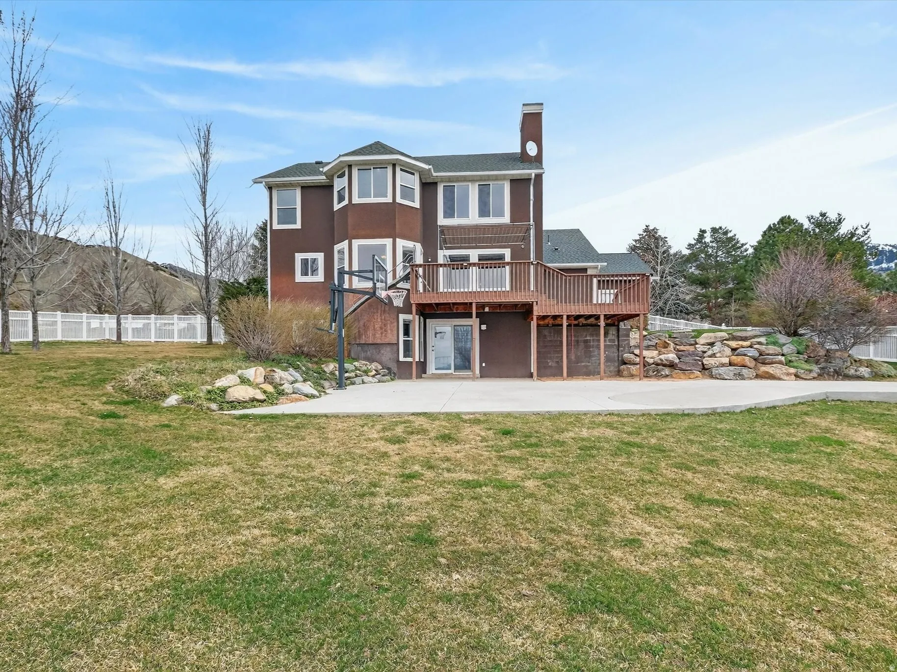Back of property featuring a wooden deck, a chimney, and stucco siding
