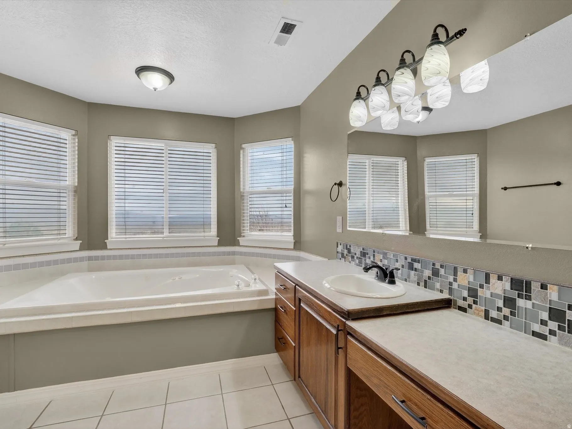 Full bath featuring vanity, a garden tub, light tile patterned floors, and a textured ceiling