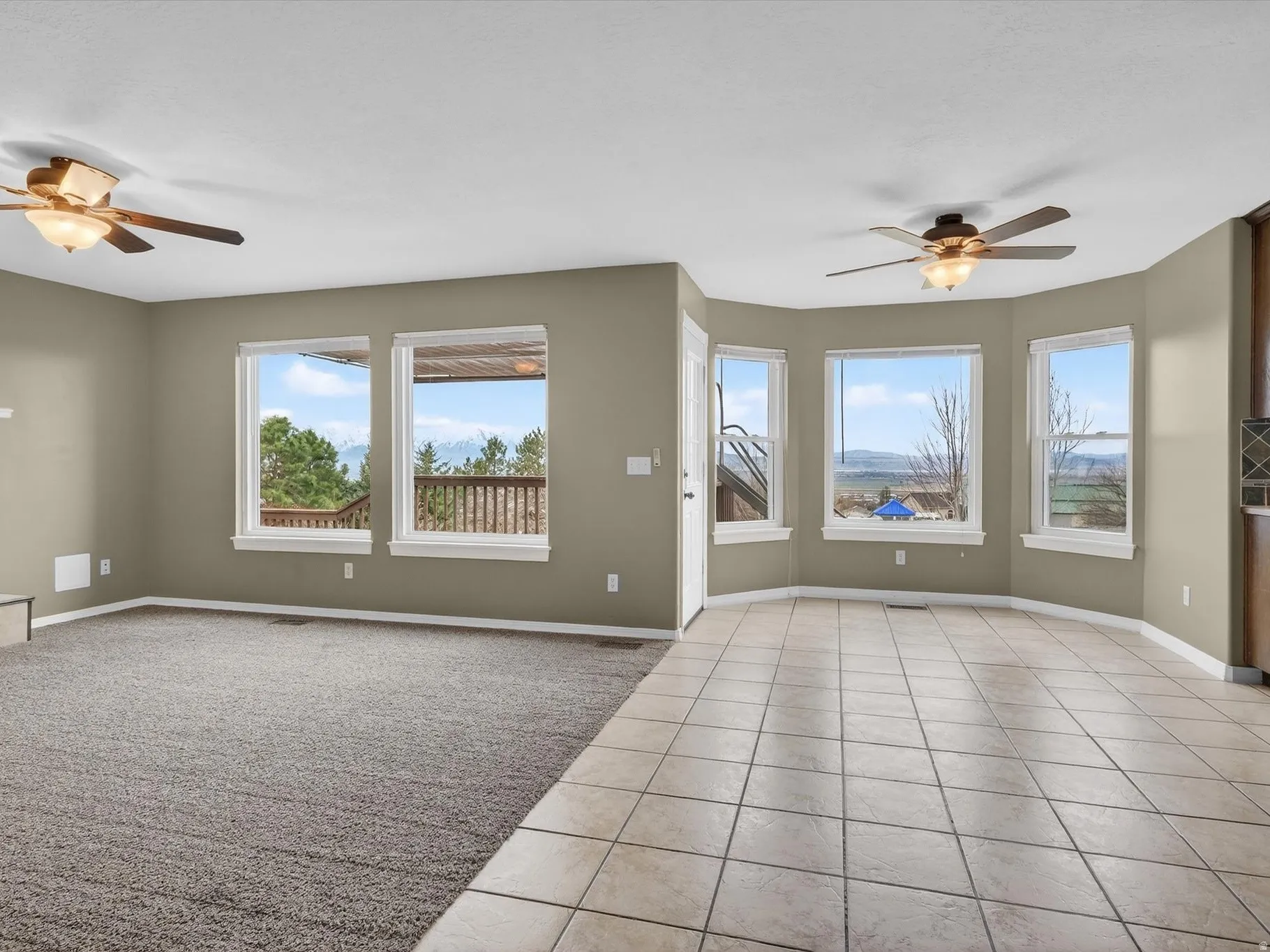 Unfurnished living room featuring ceiling fan, light carpet, and light tile patterned floors