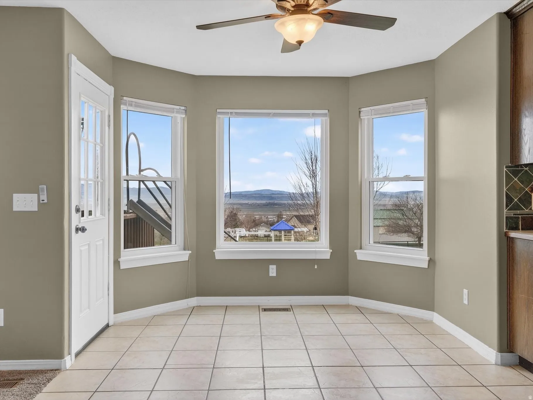 Unfurnished dining area featuring a mountain view, a ceiling fan, and light tile patterned floors