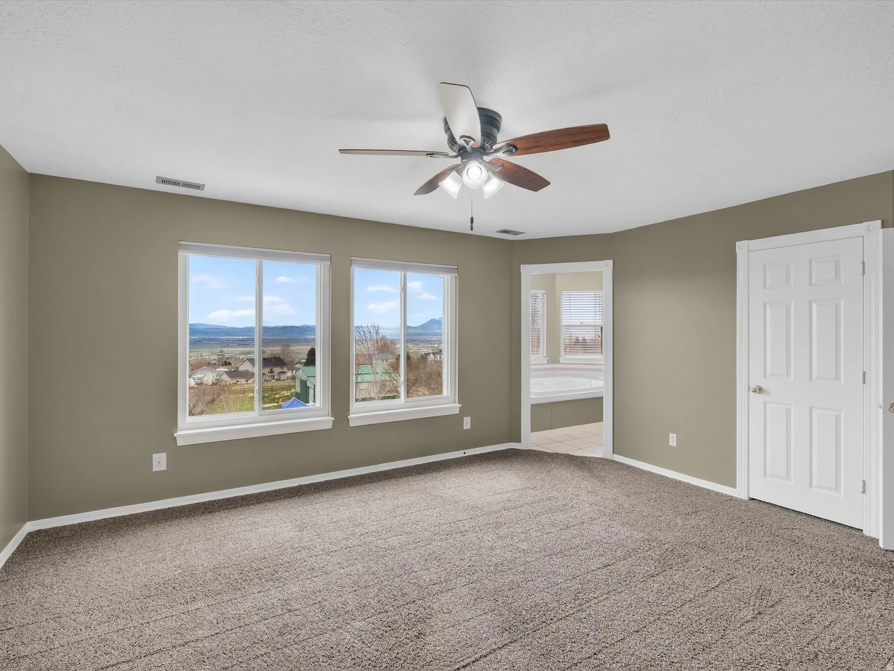 Unfurnished bedroom featuring a mountain view, ensuite bath, carpet, and ceiling fan