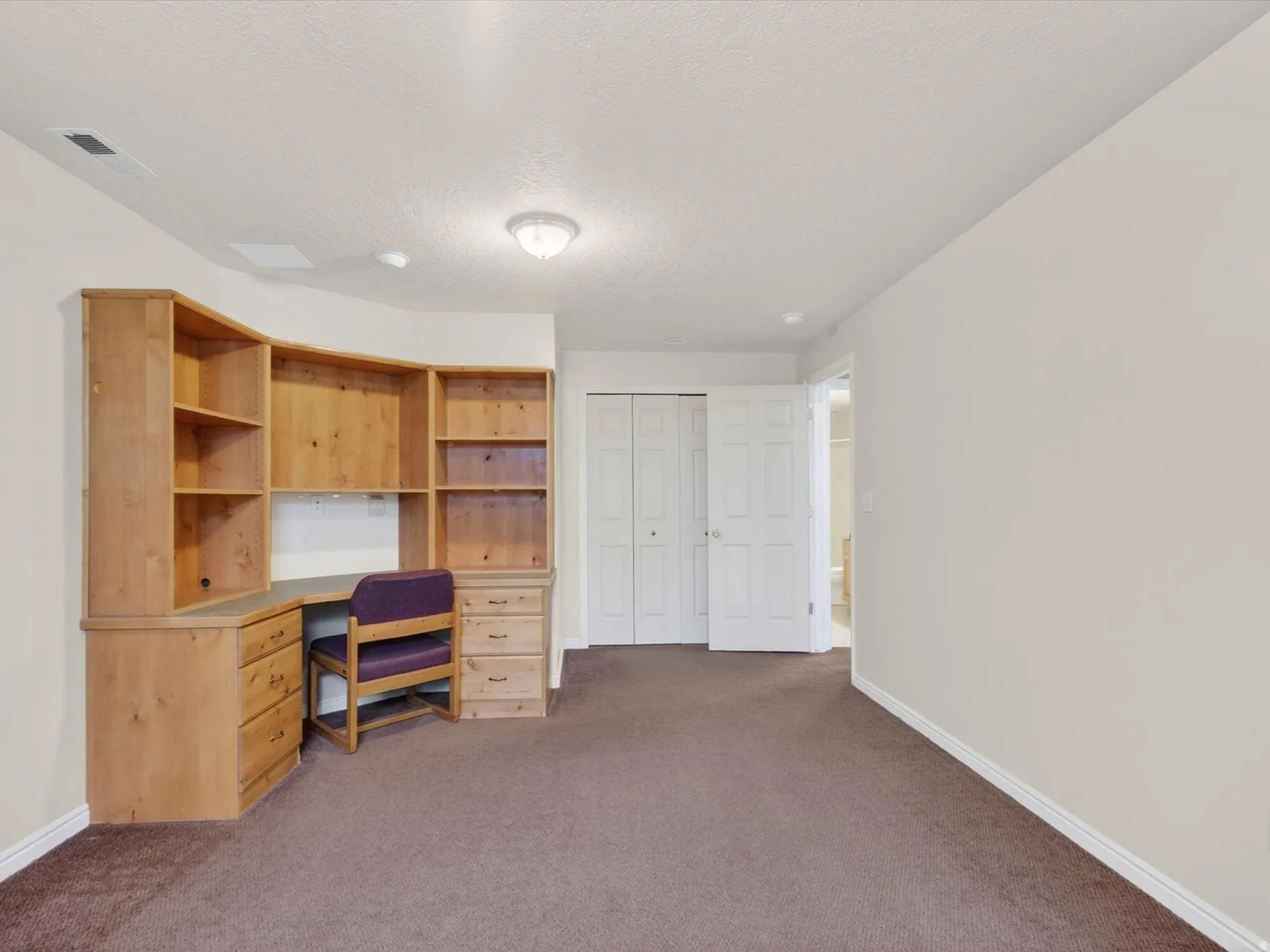 Unfurnished office featuring dark carpet and a textured ceiling