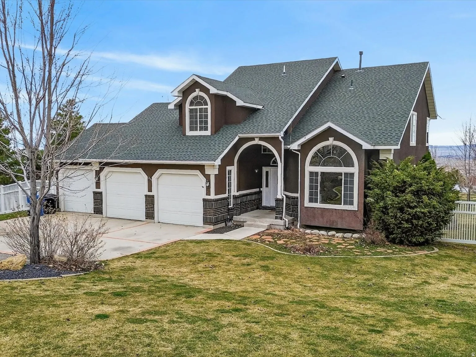 Traditional-style house with roof with shingles, a garage, concrete driveway, and stucco siding