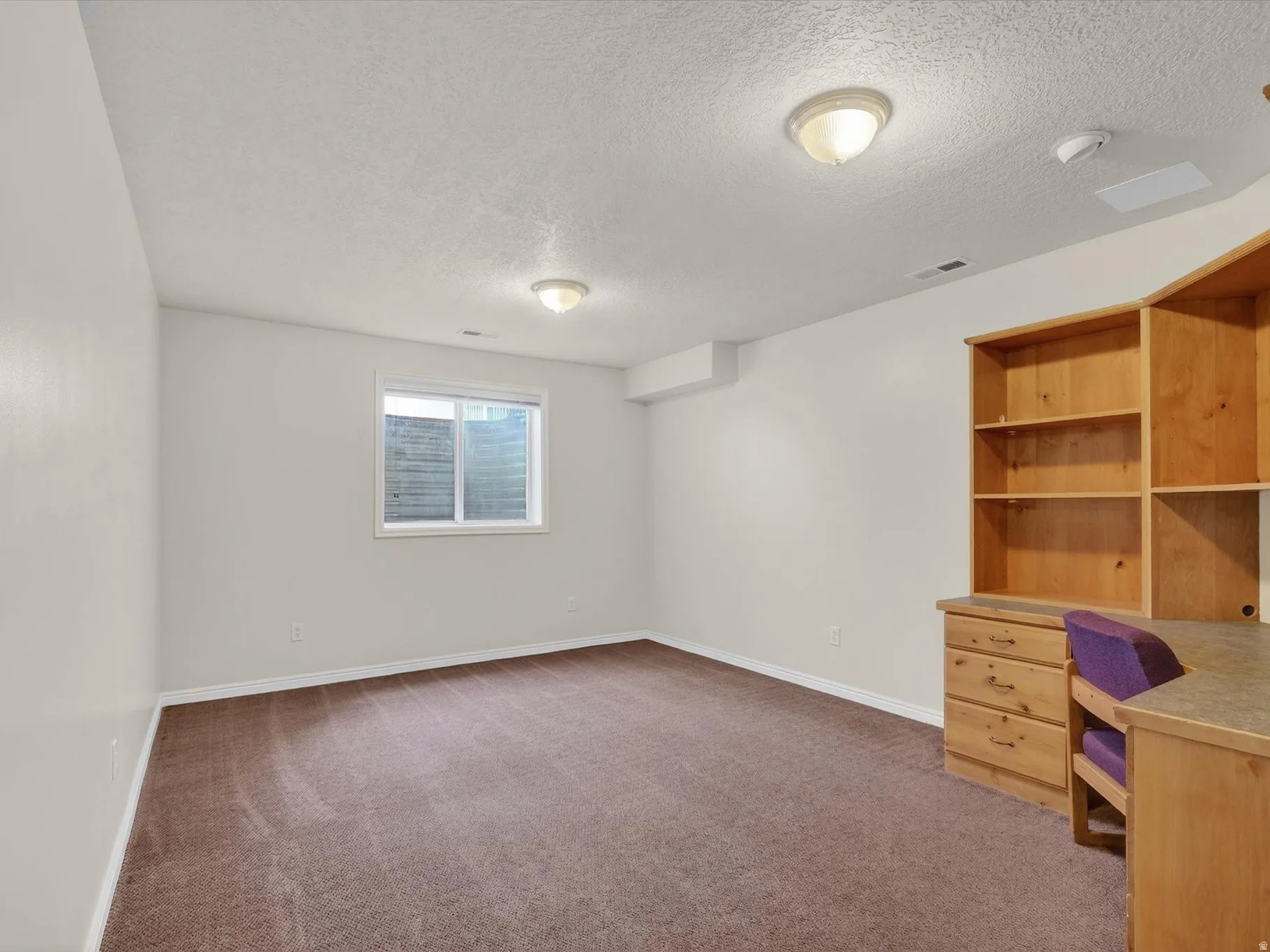 Unfurnished office with dark colored carpet and a textured ceiling