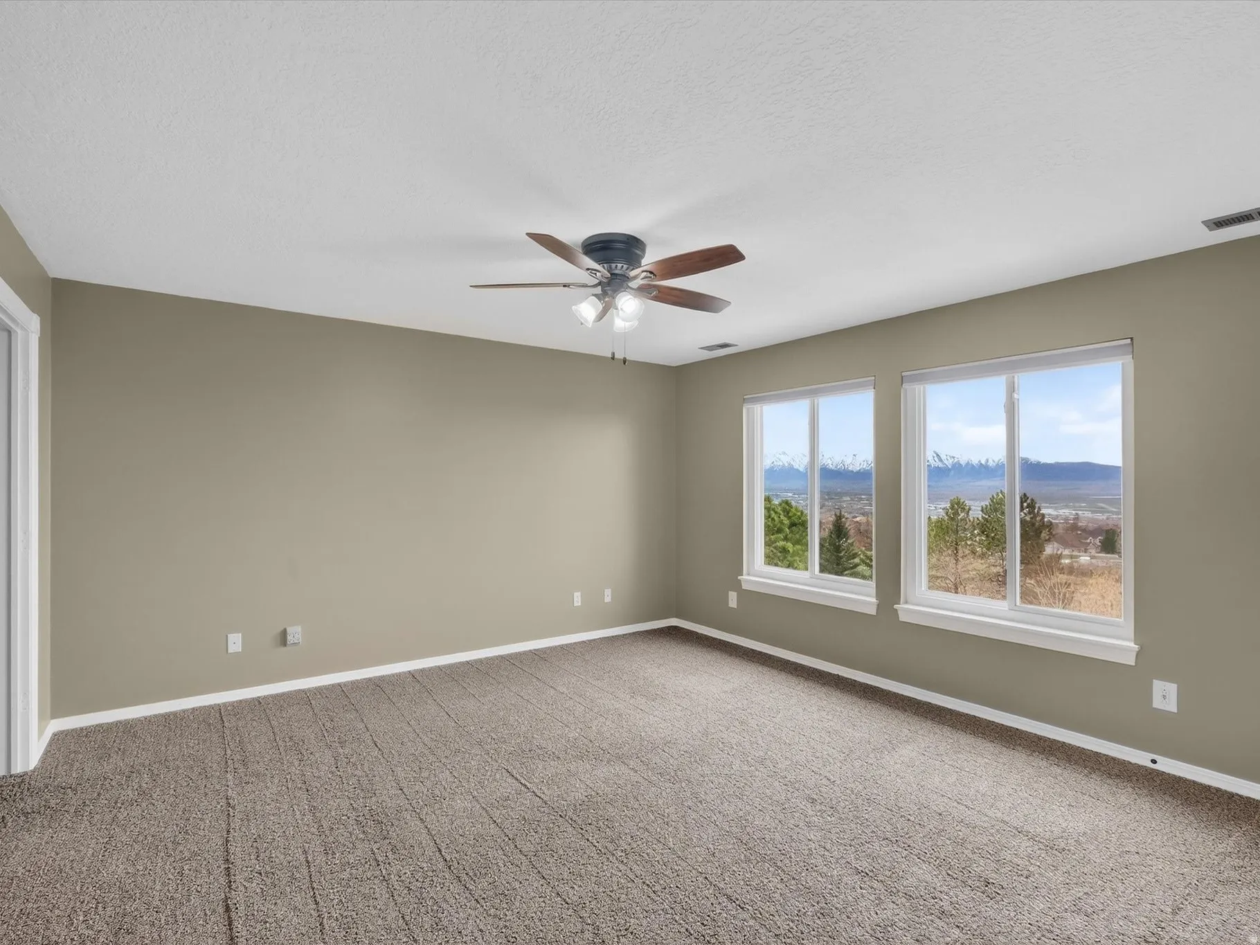 Unfurnished room with a mountain view, carpet flooring, ceiling fan, and a textured ceiling
